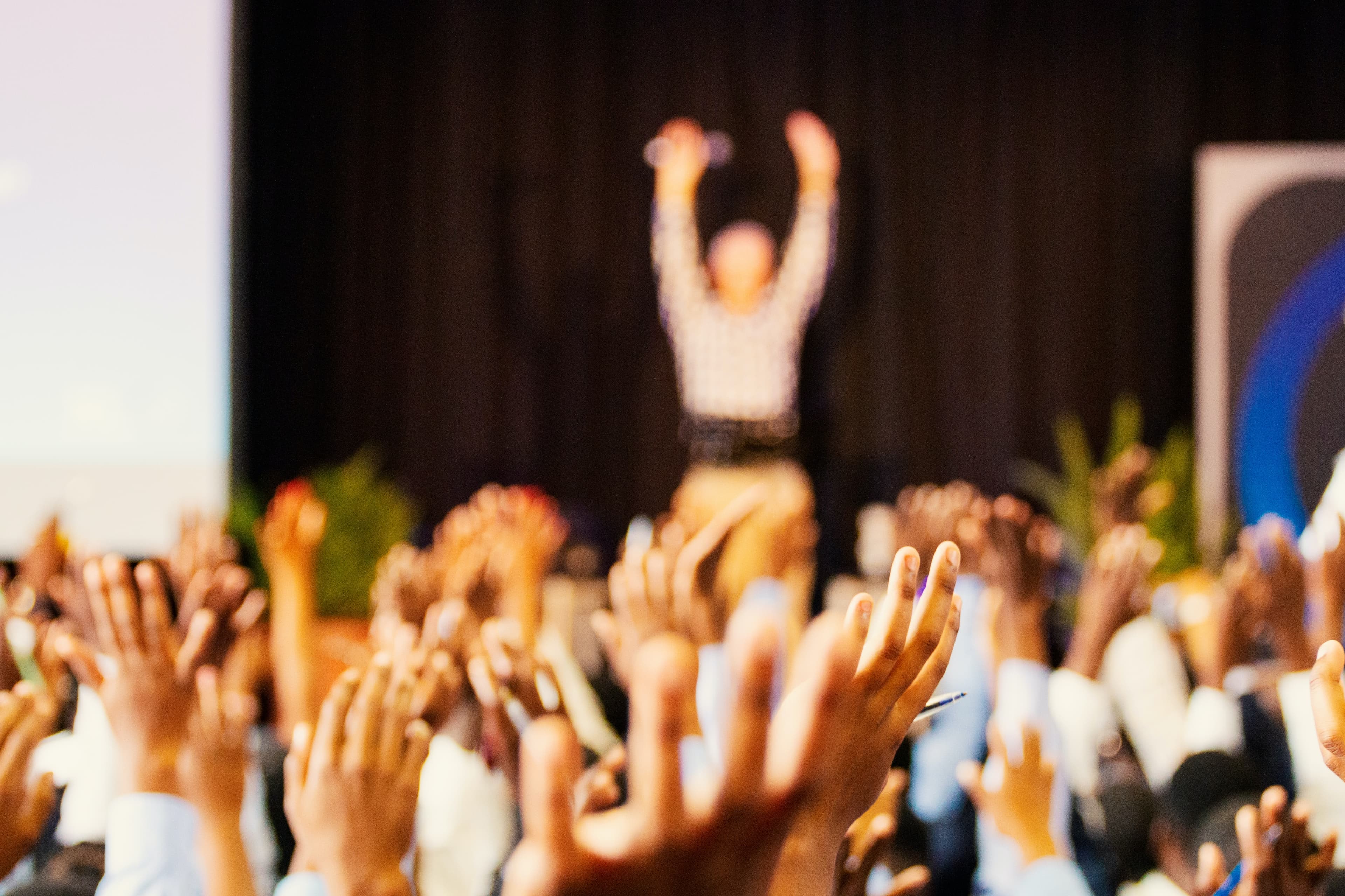 Audience raising hands in a lecture hall.